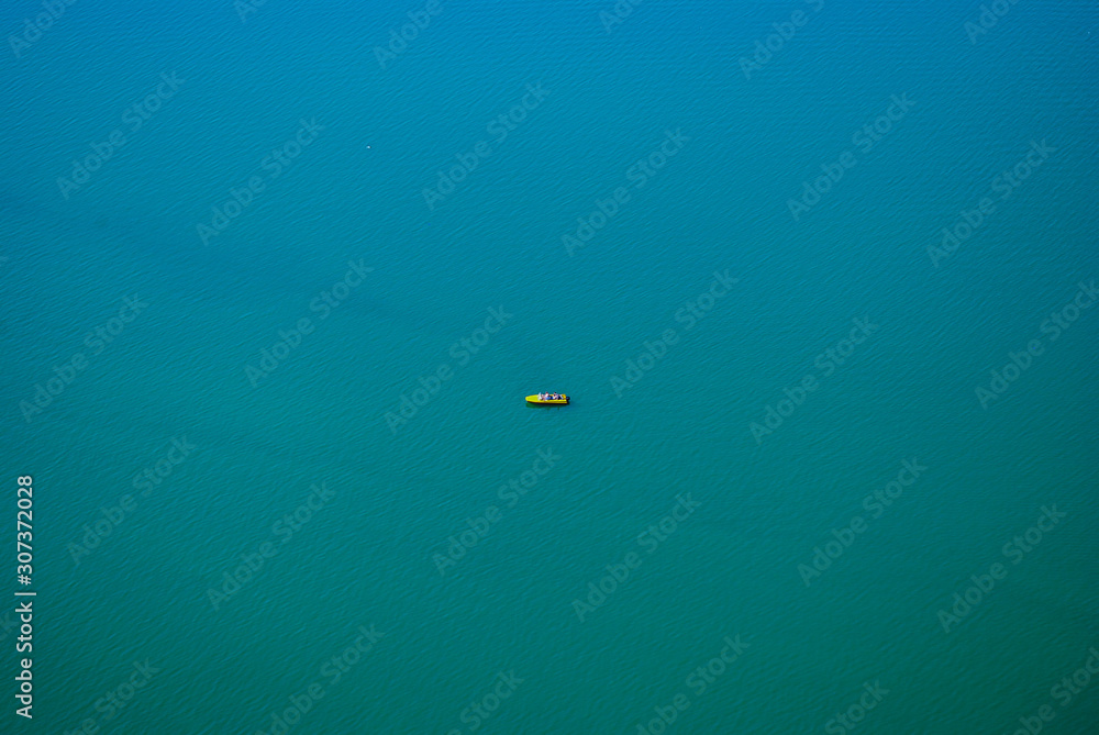 Bird's eye view photo of yellow boat in the middle of blue lake