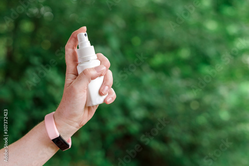 Woman using antiseptic spray outdoors