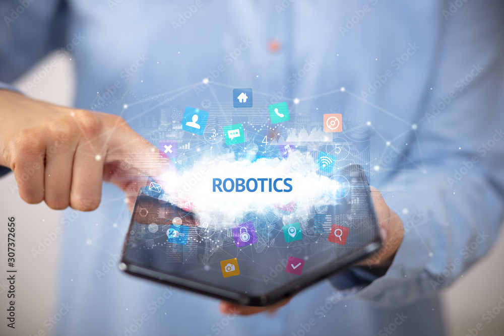 Businessman holding a foldable smartphone with ROBOTICS inscription, technology concept Businessman holding a foldable smartphone with ROBOTICS inscription, technology concept