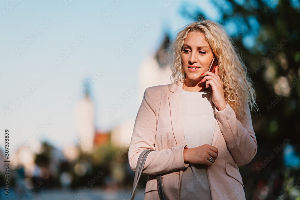 Woman walking down the street and talking on the phone Woman walking down the street and talking on the phone