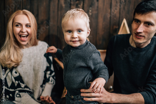 Portrait of Family Mom Dad with One Little Kid Playing in Room Decorated in Christmas Theme photo