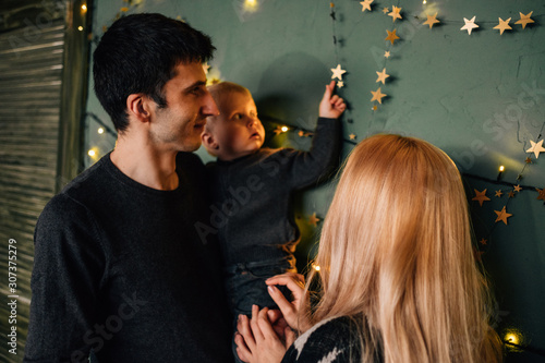 Portrait of Family Mom Dad with One Little Kid Playing in Room Decorated in Christmas Theme photo