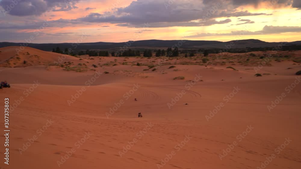 Two People Sand Boarding Down The Pink Sand Dunes During Sunset Two People Sand Boarding Down The Pink Sand Dunes During Sunset
