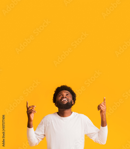 Positive afro man looking and pointing up at free space