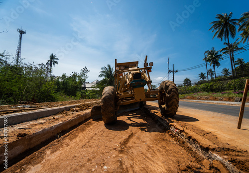 Grader is working on road construction. Grader industrial machine on construction of new roads. Heavy duty machinery working on highway. Construction equipment. Compaction of the road.