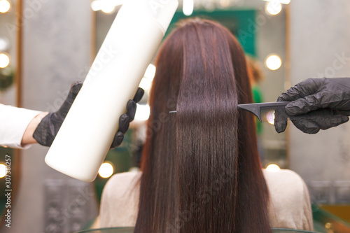 Straight and shiny hair after lamination. Hairdresser demonstrates the result of keratin hair straightening photo