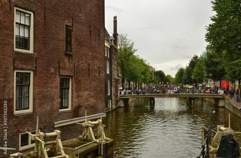 Amsterdam, Netherlands. August 2019. Typical view of the historic center: bridges over the canals are chosen by tourists to take a break to observe the particular landscape.