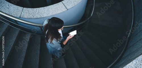 Fotografie Woman messaging on smartphone and coming downstairs