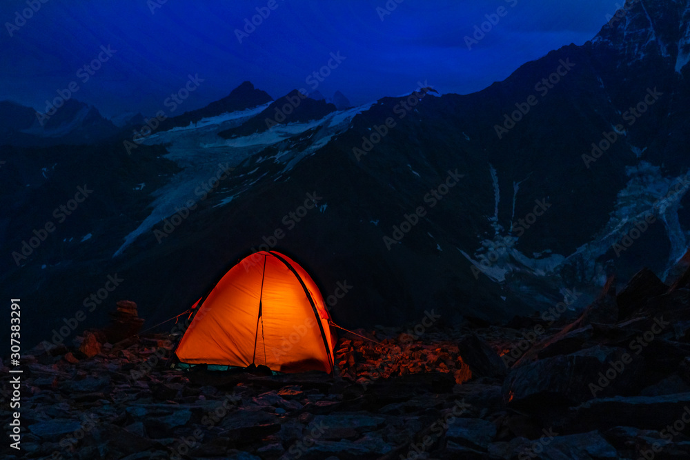 tent in the mountains highlighted inside. the mountains in the background. the dawn of time. Golden hour. a beautiful dawn. Hiking.