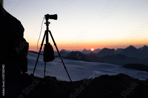 the silhouette of the tripod with the camera in the mountains at dawn