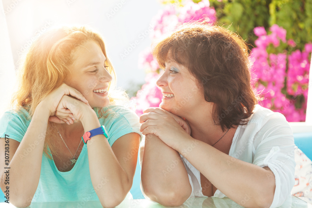 Happy beautiful young mother and adult daughter chatting laughing in the sunlight, happiness family relationship Happy beautiful young mother and adult daughter chatting laughing in the sunlight, happiness family relationship