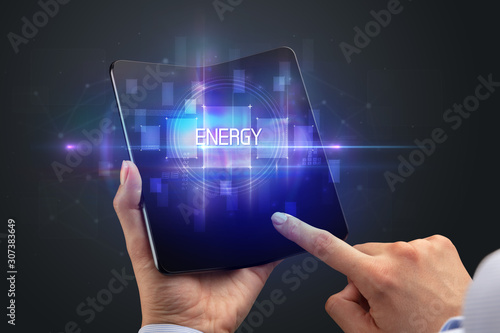 Businessman holding a foldable smartphone with ENERGY inscription, new technology concept
