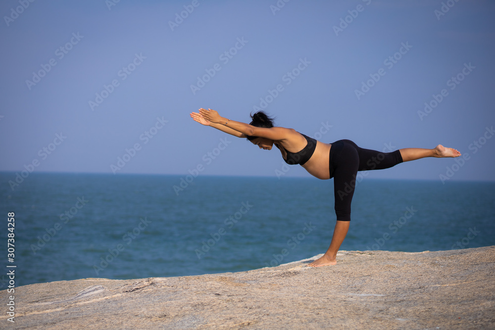 Obraz premium pregnant woman yoga pose on the beach sunset