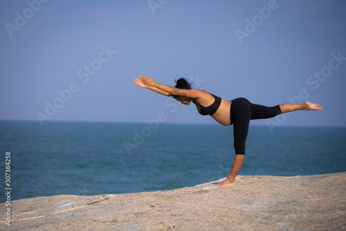 pregnant woman yoga pose on the beach sunset