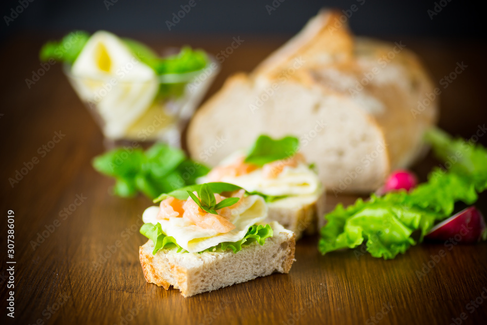 sandwich with cheese, salad leaves and red fish on a wooden sandwich with cheese, salad leaves and red fish on a wooden