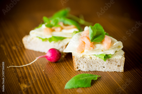 sandwich with cheese, salad leaves and red fish on a wooden