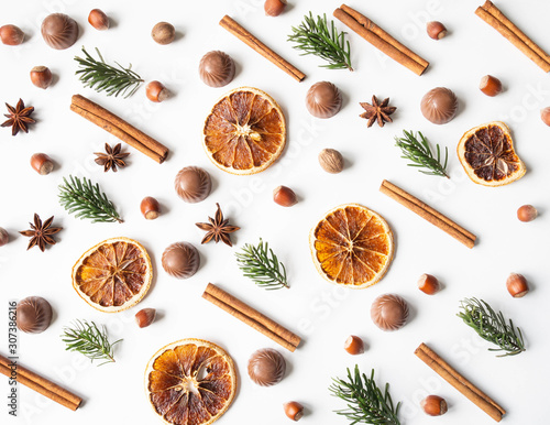 Sweet festive pastry composition with chocolate, dry orange slices, fir tree, nuts and spices on a white background.