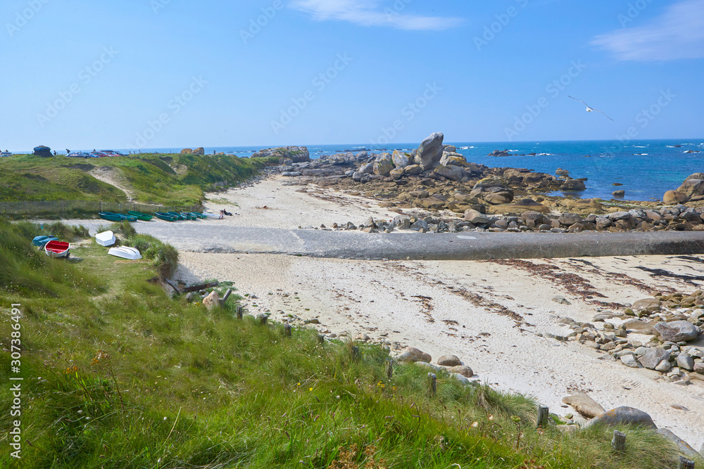 Small asphalt path to the coast, landscape with grass dunes, sand, rocks and blue water, sunny summer feeling