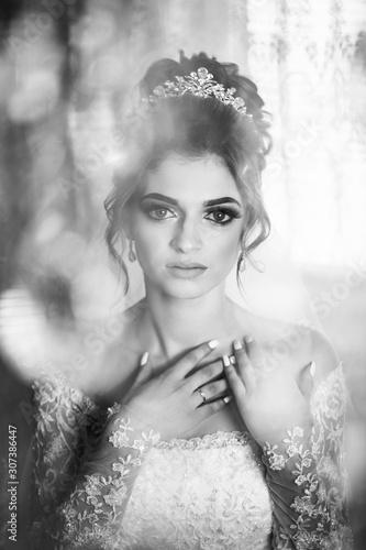 Black and white photo. Gorgeous female bride. Beautiful bride with makeup and hair style. Sexy bride posing in luxury interior. Wedding morning of the bride. Newlywed woman final preparation for weddi