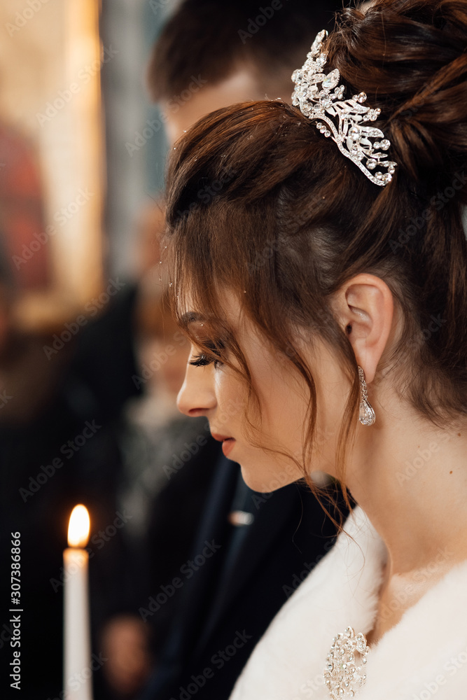 Spiritual couple, bride and groom holding candles during wedding ceremony in christian church, emotional moment during ceremony for man and woman. Newlyweds in the church. Church religious details.