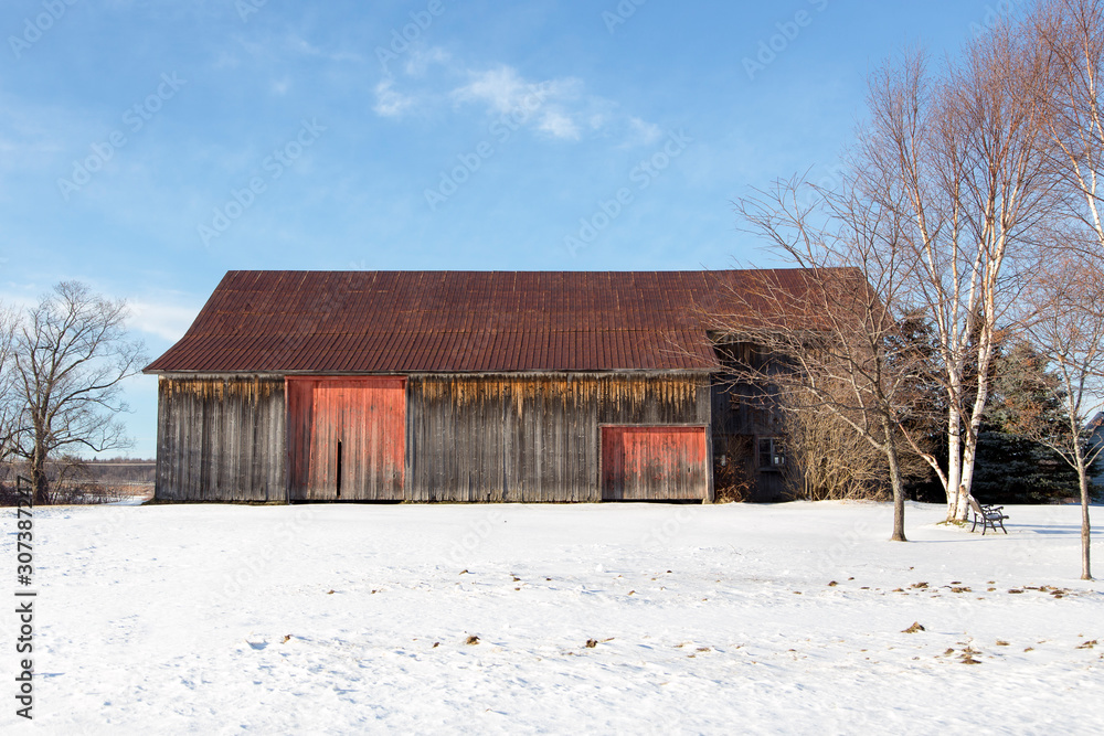 Large old wooden barn with rusting metal roof seen in rural area during an early winter sunny morning, Saint-Augustin-de-Desmaures, Quebec, Canada Large old wooden barn with rusting metal roof seen in rural area during an early winter sunny morning, Saint-Augustin-de-Desmaures, Quebec, Canada