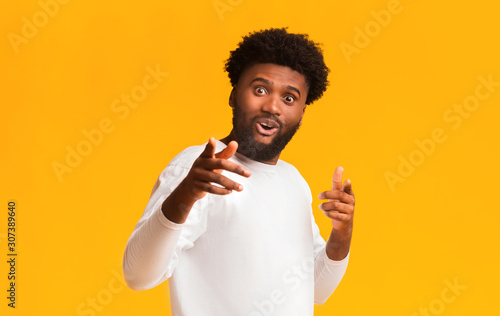 Excited black man greeting happily, indicating to camera