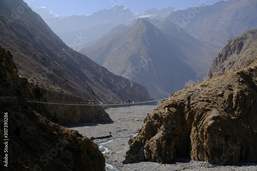 Dramatic view of the suspension bridge over the river in the Kali Gandaki Valley. Nepal  Mustang  Himalayas  trekking around Annapurna