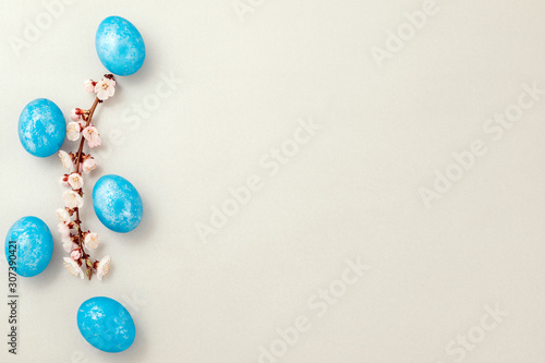 Blue easter eggs with apricot twig on silver textured paper. Top view. Copy space