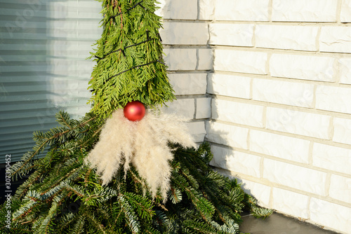 self made christmas imp figure from fir branches sitting in entrance from the house