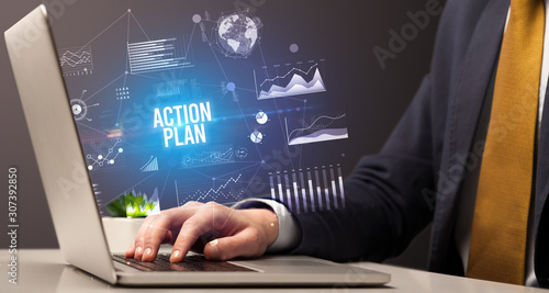 Businessman working on laptop with ACTION PLAN inscription, new business concept