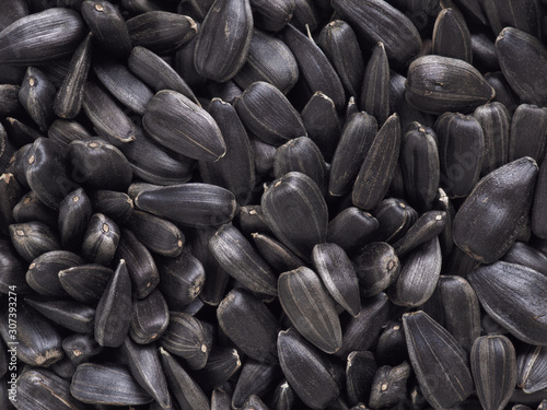 The surface of black sunflower seeds. Illustration or dark black background or wallpaper. Winter food for wild birds. View from above. Close-up