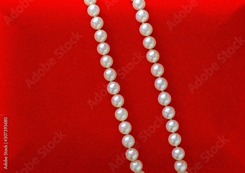 Beautiful natural pearl necklace laid on red velvet jewelry box.