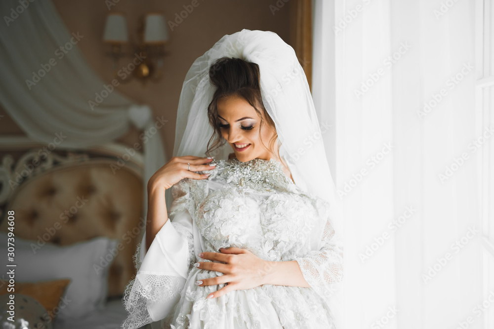 Gorgeous bride in robe posing and preparing for the wedding ceremony face in a room Gorgeous bride in robe posing and preparing for the wedding ceremony face in a room