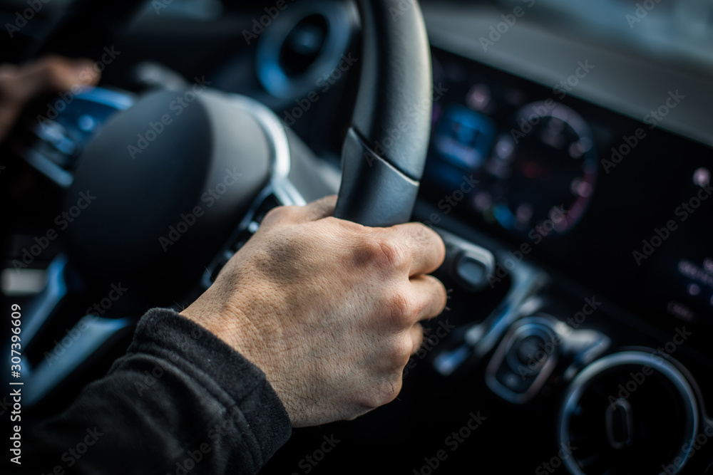 Naklejka premium Man's hand holding the steering wheel