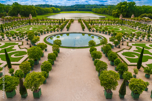 Great aerial view of the beautiful Orangery parterre in the Gardens of Versailles. It consists of four grass sections, a circular pool, orange trees, palm trees, oleander and many other plants. 