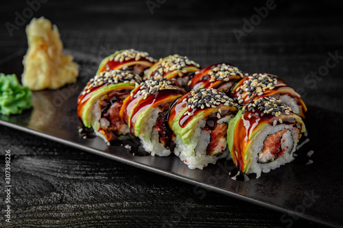 Sushi roll with salmon, avocado, shrimp, cucumber, tobiko and philadelphia cheese on black background. Sushi menu. Japanese food.