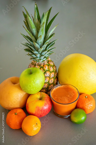 Different tropical fruits and orange smoothie on grey background  healthy eating lifestyle concept