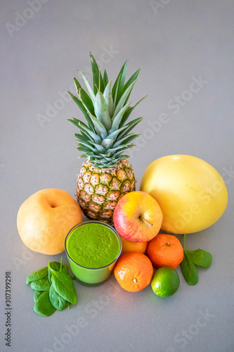 Different tropical fruits and green smoothie on grey background  healthy eating lifestyle concept