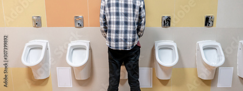 Foto young man in the public toilet, standing next to the urinal in the trade center