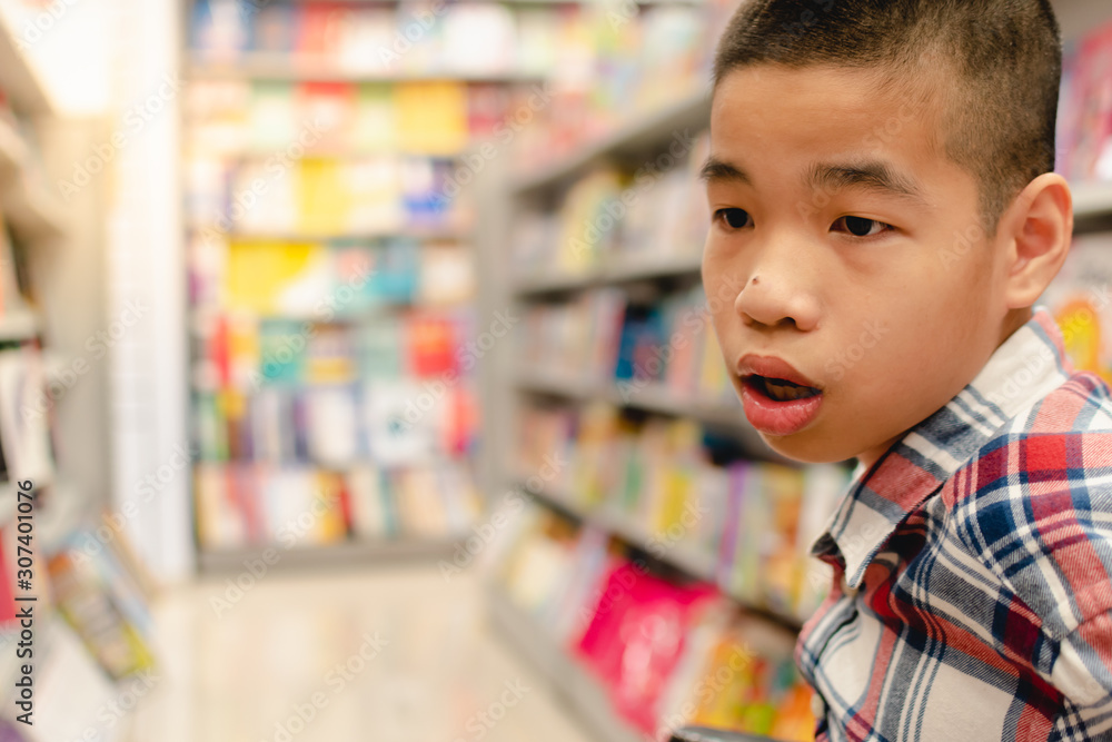 Disabled child on wheelchair having fun choosing books from shelves, Special children's lifestyle, Life in the education age of special need kids, Happy disability kid concept, Selective focus. Disabled child on wheelchair having fun choosing books from shelves, Special children's lifestyle, Life in the education age of special need kids, Happy disability kid concept, Selective focus.