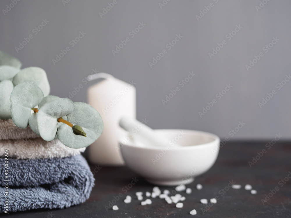 Wellness und Spa, Handtücher, Kerze und eine Schüssel mit Badesalz auf einem grauen Hintergrund Wellness und Spa, Handtücher, Kerze und eine Schüssel mit Badesalz auf einem grauen Hintergrund