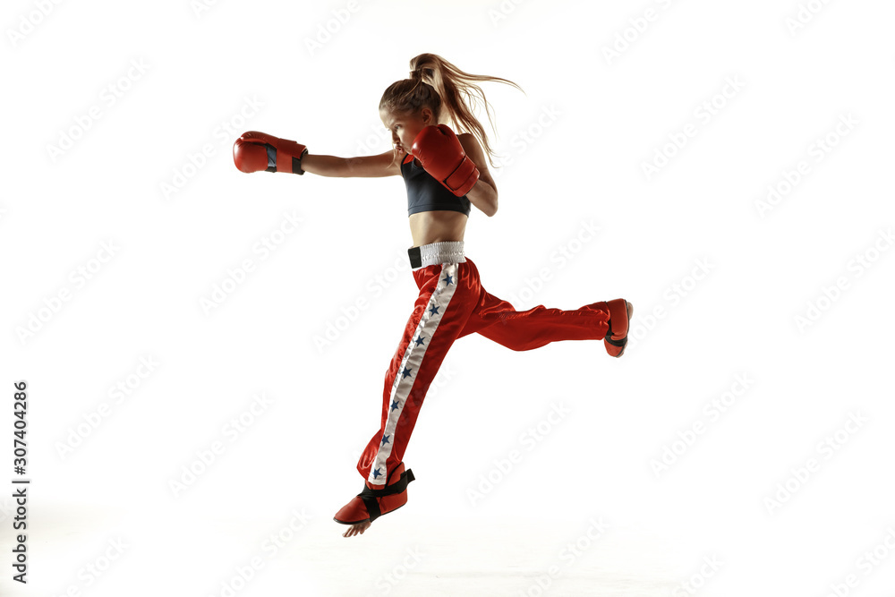 Young female kickboxing fighter training isolated on white background. Caucasian blonde girl in red sportswear practicing in martial arts. Concept of sport, healthy lifestyle, motion, action, youth.