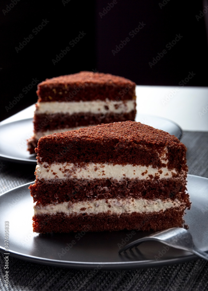 two pieces of chocolate cake on a dark plate two pieces of chocolate cake on a dark plate