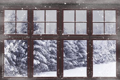 Window frame with snowy fir trees outside photo