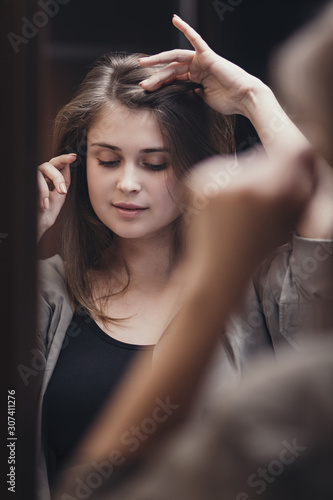 portrait of a beautiful pretty girl in the mirror reflection, young woman posing with soft hand movements near the face, concept of fashion, courage to dream and look in a new way
