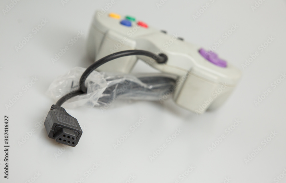 Fototapeta premium Retro vintage games console controller purple black white red blue green yellow isolated dirty used video game marked scuff wire cable kids playing adults nostalgia old technology shop studio lighting