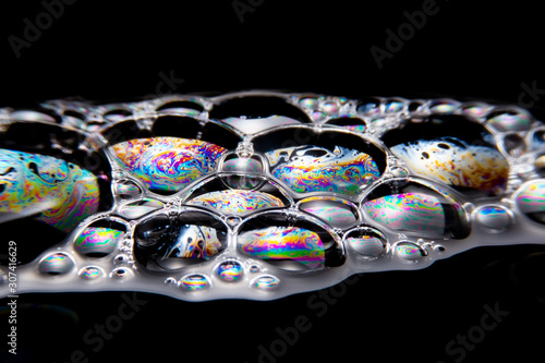 Close up of the Colorful bubbles on a black background. Refection of the Soap bubbles on the water surface on black background.