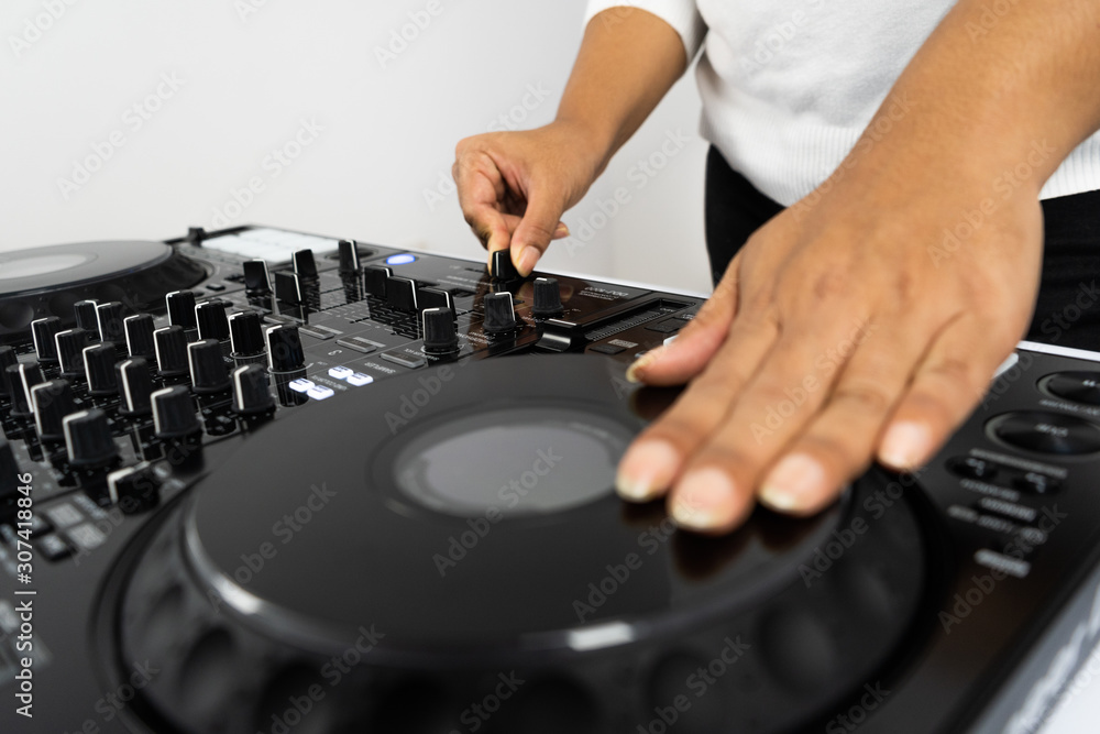 Hands of DJ mixing tracks on professional sound mixer.Fashionable rings on fingers of girl disc jockey playing music.Closeup,knobs and regulators in focus.Girl dj play music tracks at house party Hands of DJ mixing tracks on professional sound mixer.Fashionable rings on fingers of girl disc jockey playing music.Closeup,knobs and regulators in focus.Girl dj play music tracks at house party