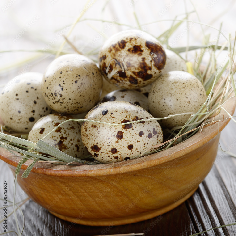 Fresh organic quail eggs in wooden bowl on rustic kitchen table. Space for text Fresh organic quail eggs in wooden bowl on rustic kitchen table. Space for text