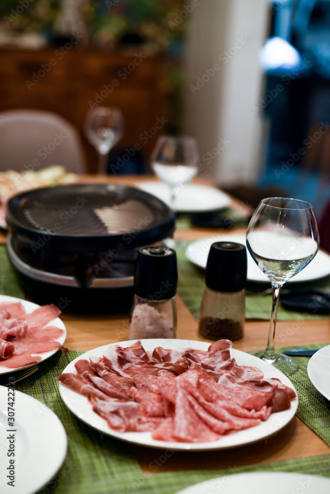 Raclette table setting with cheese and delicatessen 